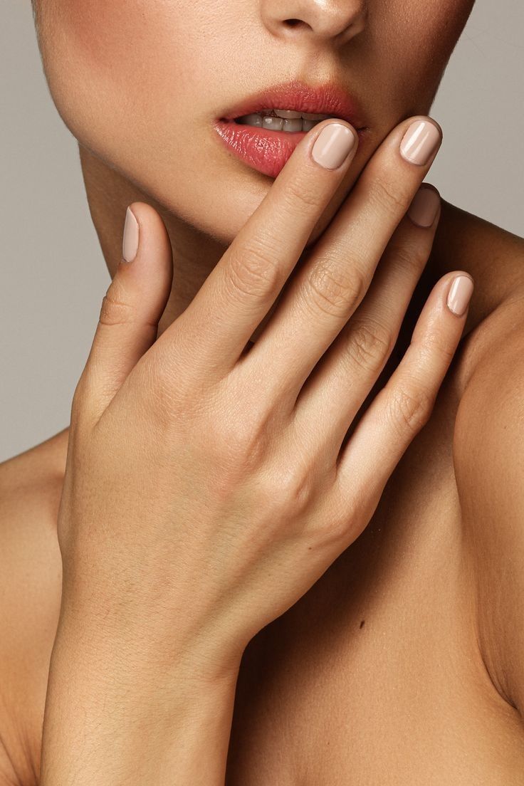 Close-up of a woman's hand and neck with soft focus on the face.