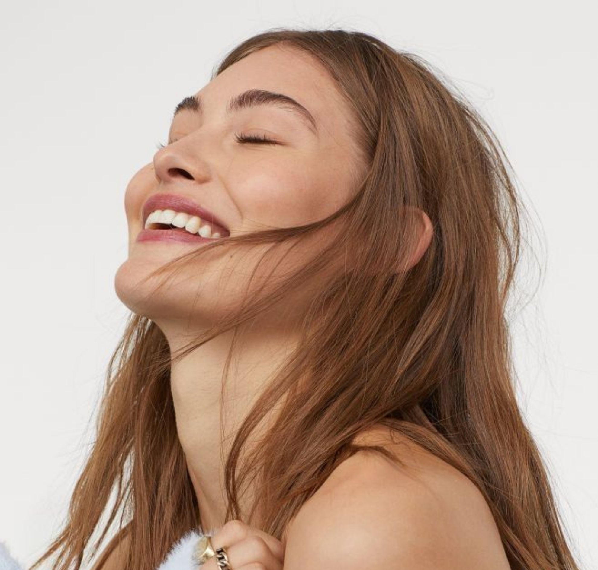 Woman with long brown hair smiling against a white background