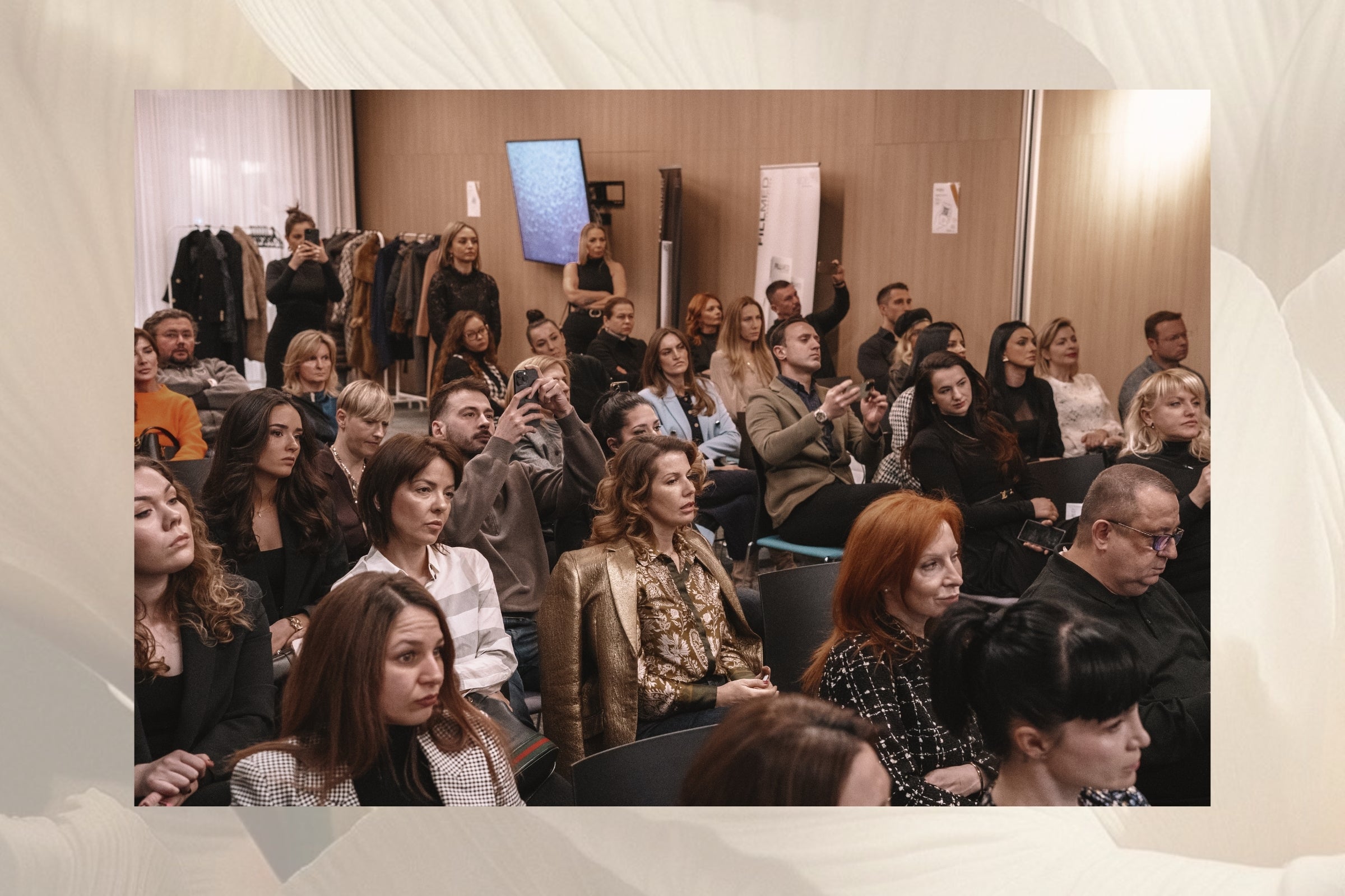 Audience attending a presentation in a conference room with a screen and chairs.