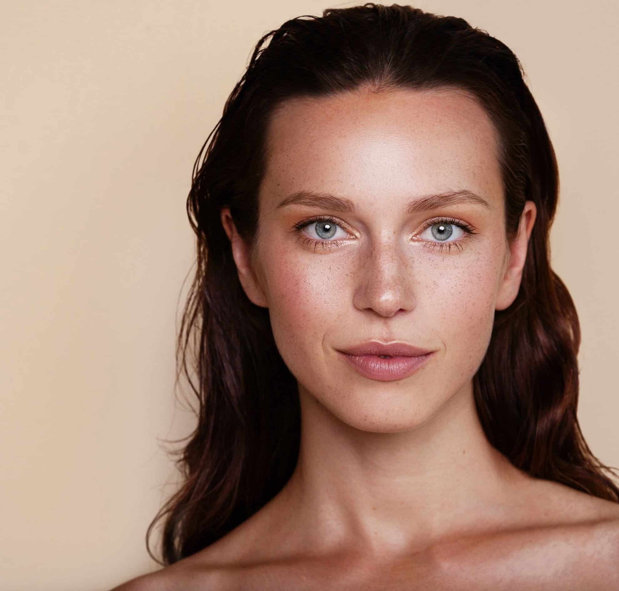 Woman with a neutral expression on a beige background
